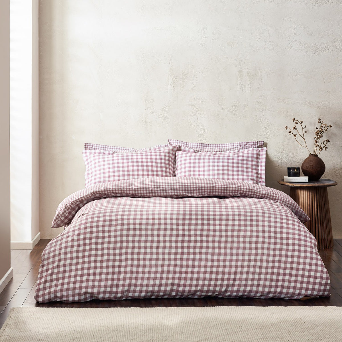 Barton Cotton Gingham Duvet Cover Set in Berry dressed on a bed with matching pillowcases, shown in a bedroom with a wooden side table and neutral walls.