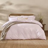 Barton Cotton Gingham Duvet Cover Set in blush, styled on a bed with pillowcases and a grey throw, cane headboard and bedroom setting.