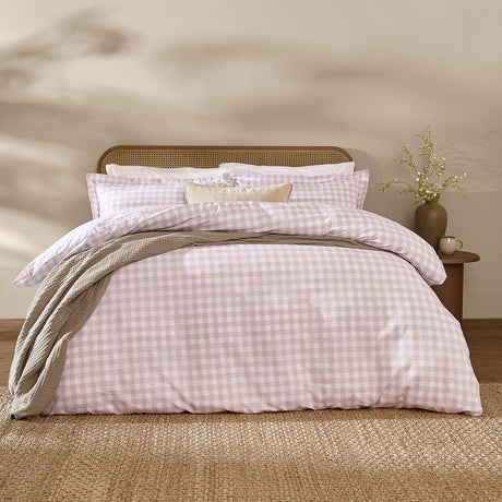 Barton Cotton Gingham Duvet Cover Set in blush, styled on a bed with pillowcases and a grey throw, cane headboard and bedroom setting.