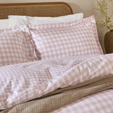 Barton Cotton Gingham Duvet Cover Set in Blush styled on a bed with matching pillowcases, pink and white check cotton percale, shown against a wooden headboard and neutral throws.