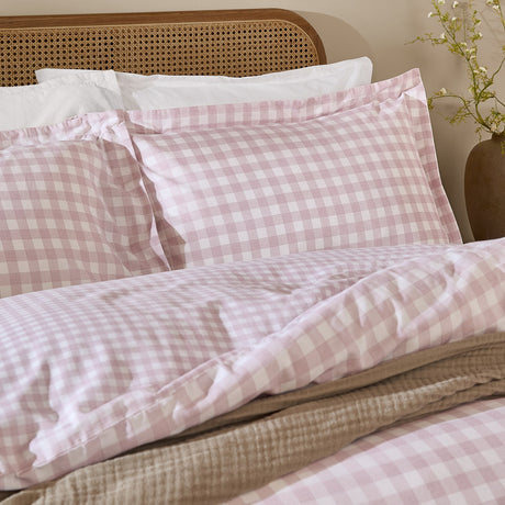Barton Cotton Gingham Duvet Cover Set in Blush styled on a bed with matching pillowcases, pink and white check cotton percale, shown against a wooden headboard and neutral throws.