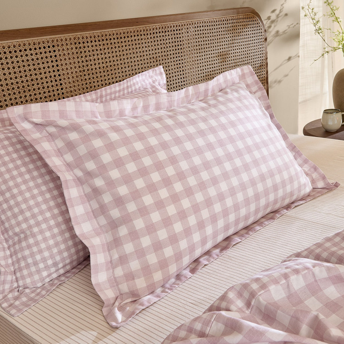 Barton Cotton Gingham Duvet Cover Set in blush, showing pink and white check pillow shams on a bed with a cane headboard and matching duvet corner visible.