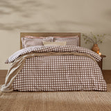 Barton Cotton Gingham Duvet Cover Set in chocolate brown and white check on a bed with matching pillowcases, set in a bedroom with wooden headboard and side table.