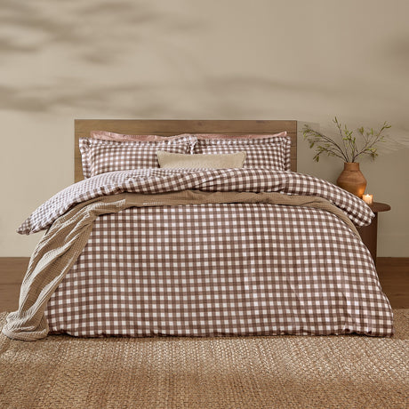 Barton Cotton Gingham Duvet Cover Set in chocolate brown and white check on a bed with matching pillowcases, set in a bedroom with wooden headboard and side table.