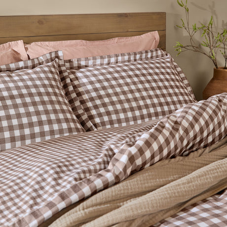 Barton Cotton Gingham Duvet Cover Set in chocolate brown and white, shown with matching pillowcases on a bed with a wooden headboard and pink sheets beneath.