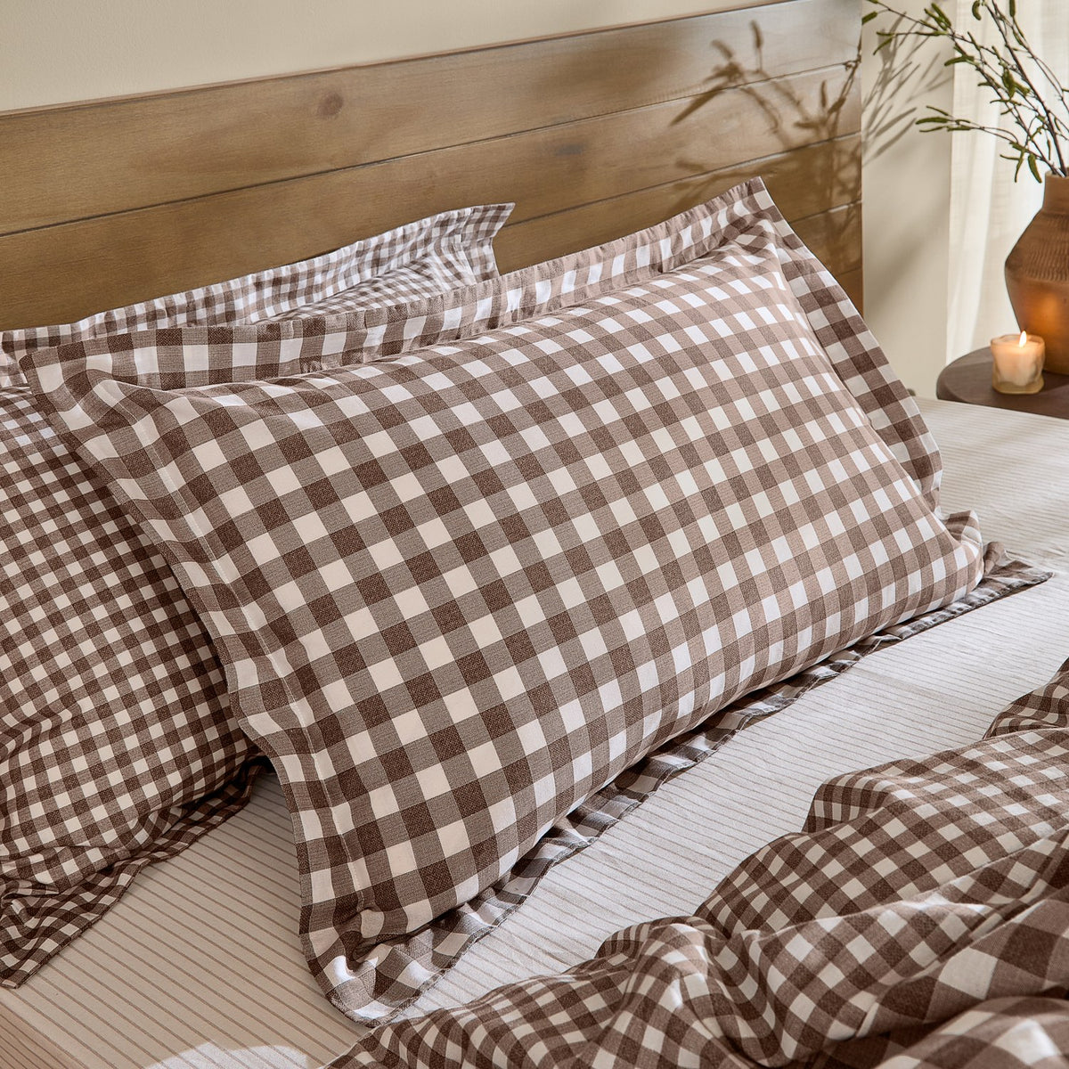 Barton Cotton Gingham Duvet Cover Set in chocolate brown and white, shown on a bed with matching pillow shams against a wooden headboard.