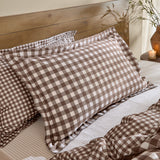 Barton Cotton Gingham Duvet Cover Set in chocolate brown and white, shown on a bed with matching pillow shams against a wooden headboard.