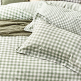 Barton Cotton Gingham Duvet Cover Set in Forest, showing green and white check pillowcases and duvet cover on a bed with a textured green throw folded alongside.