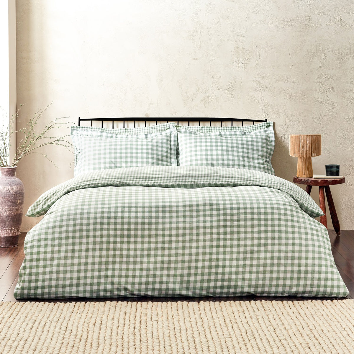 Barton Cotton Gingham Duvet Cover Set in Forest dressed on a bed with matching pillowcases, styled in a bedroom with a black metal headboard and wooden side table.