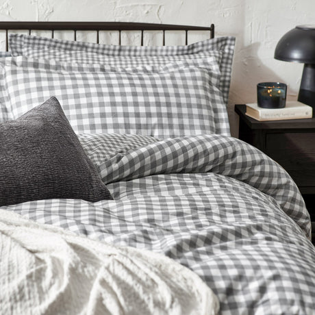 Barton Cotton Gingham Duvet Cover Set in grey and white, styled on a bed with matching pillowcases, a textured charcoal cushion, and a cream throw, in a bedroom setting.