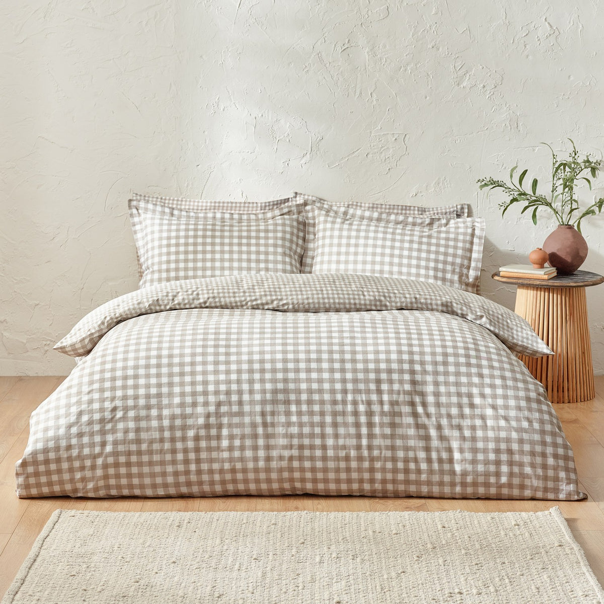 Barton Cotton Gingham Duvet Cover Set in Natural on a bed with matching pillowcases, styled in a bedroom with a wooden side stool and woven rug.