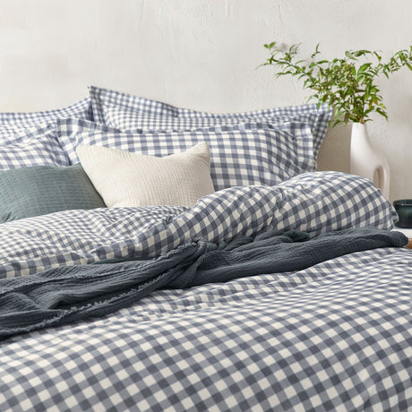 Barton Cotton Gingham Duvet Cover Set in navy, styled on a bed with matching pillowcases, a cream cushion and teal throws, in a bedroom setting.
