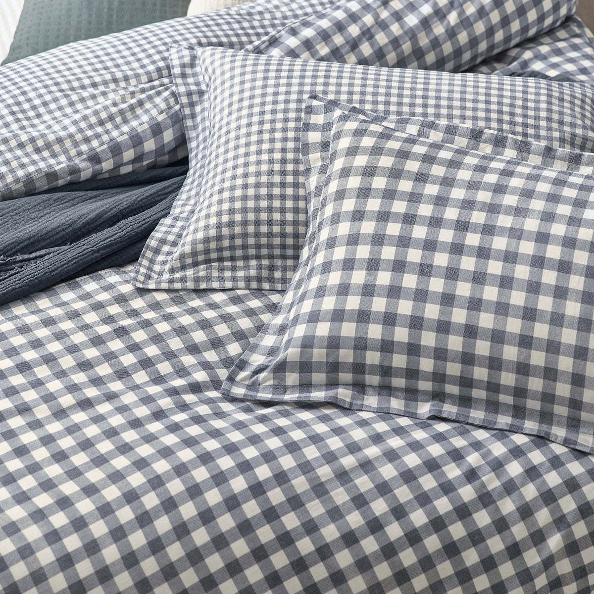 Barton Cotton Gingham Duvet Cover Set in Navy, shown with matching pillowcases featuring a navy and cream check pattern with flanged edges on a bed.