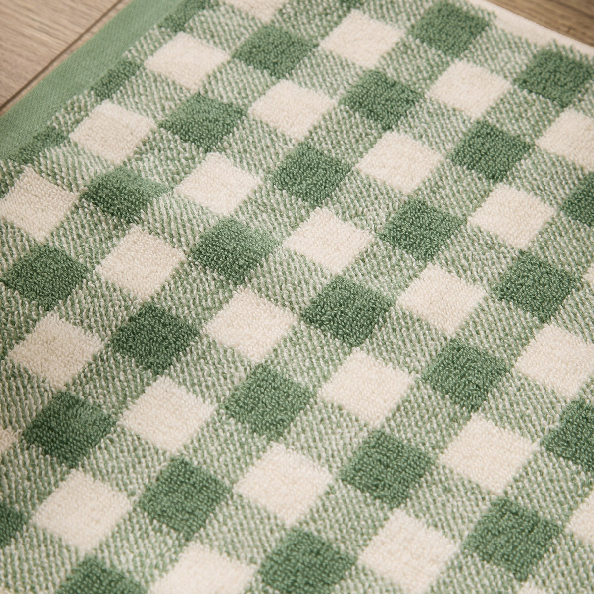 Close-up of the Barton Gingham Cotton Bath Mat in forest green, showing the yarn-dyed check pattern in green and cream cotton pile.