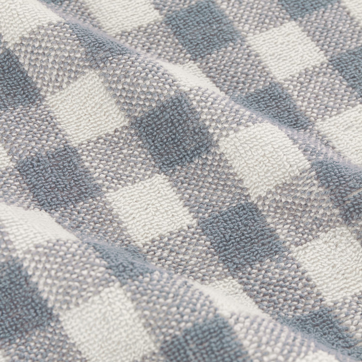 Close-up of Barton Gingham Cotton Towels in denim blue, showing the woven check pattern and looped terry texture of the cotton fabric.