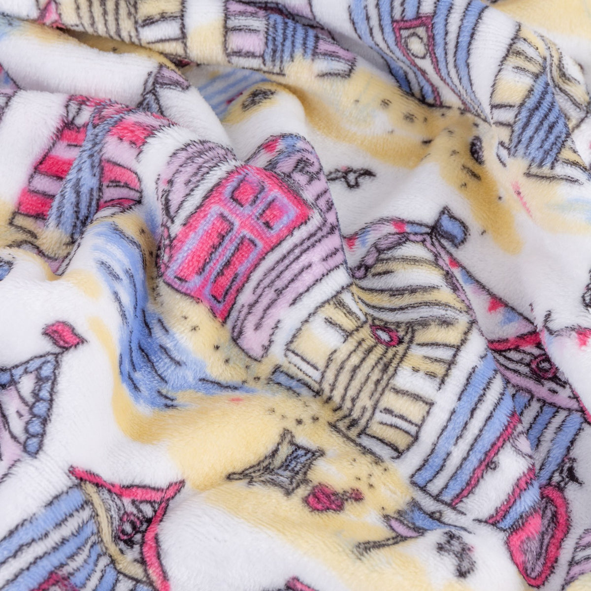 Close-up of the Beach Huts Printed Polyester Throw, rumpled fleece fabric showing illustrated beach huts in pink, blue, yellow and lilac on a cream background.
