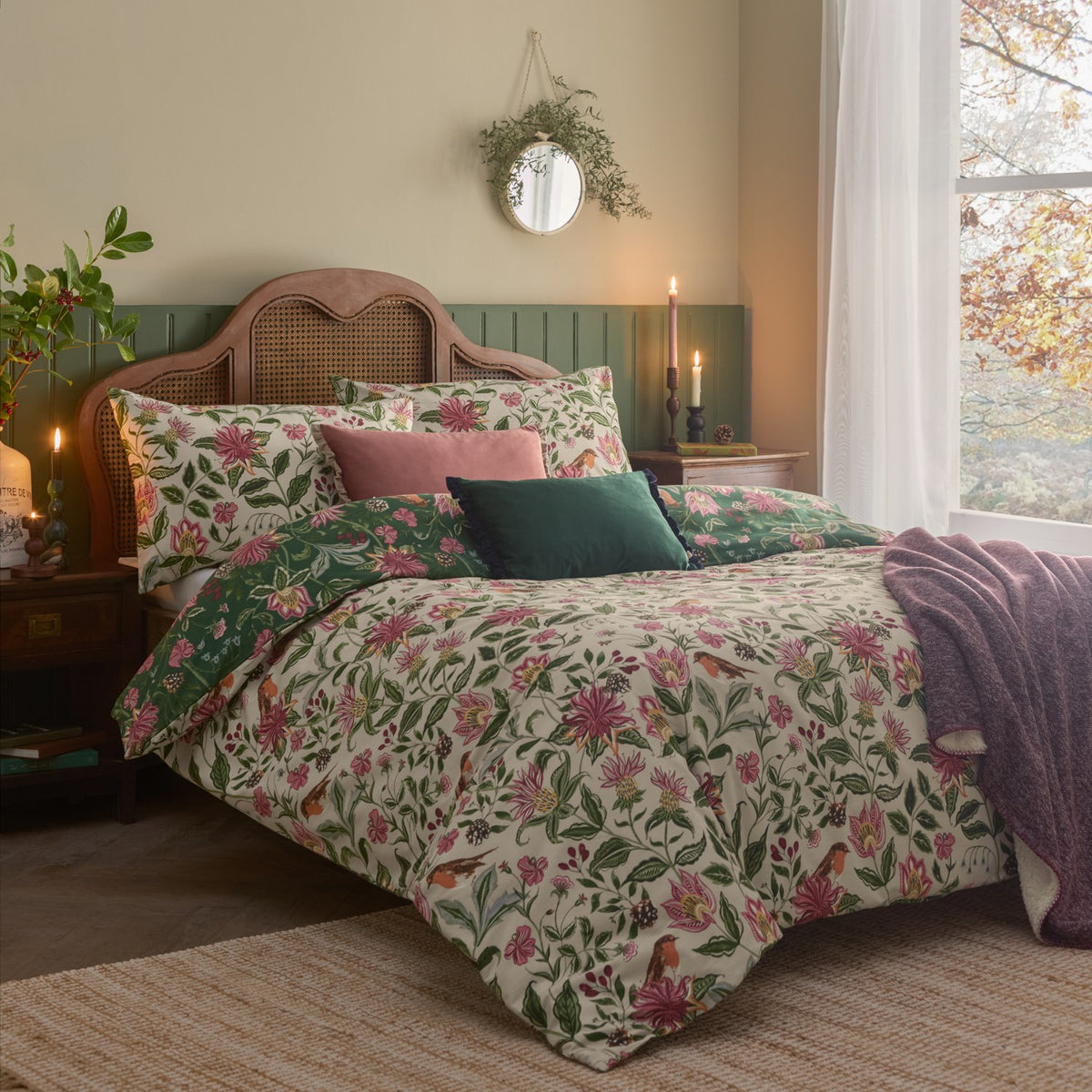 Beatrice Reversible Floral Duvet Cover Set in multicolour on a bed, cream side shown with pink and green botanical print, robin motif and matching pillowcases in a cosy bedroom setting.