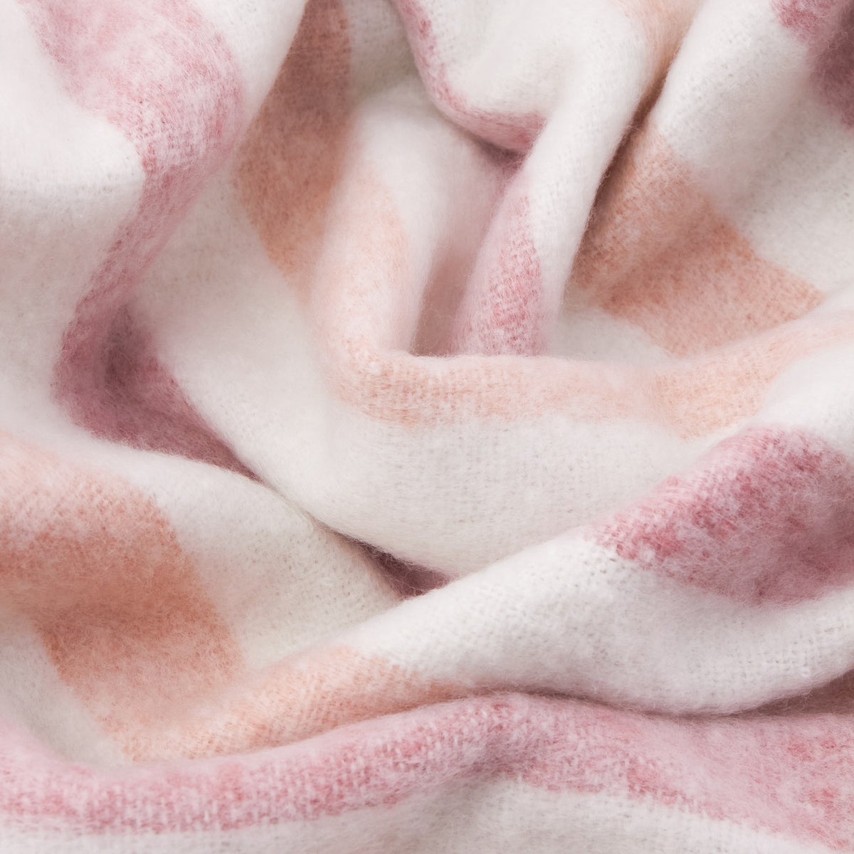 Close-up of the Beechwood Striped Cotton Throw in Camellia, showing soft woven cotton fabric in ivory with pink and dusky rose stripes, gently rumpled to reveal texture.