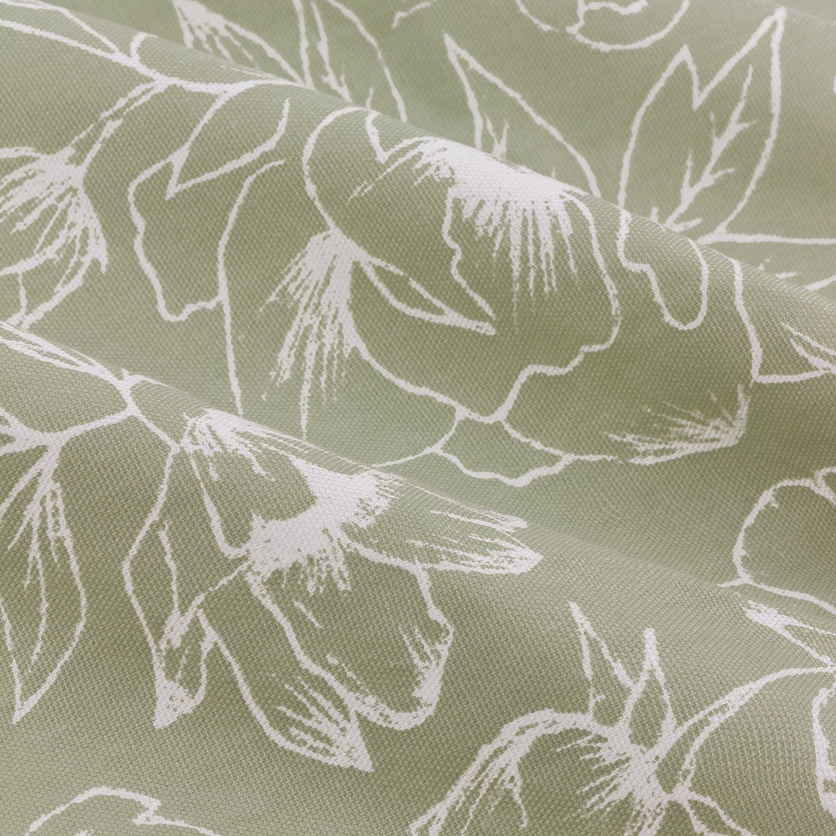 Close-up of Bella pencil pleat curtain fabric in sage green cotton, showing fine white linework of peony and open-flower motifs across soft draped folds.
