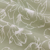 Close-up of Bella pencil pleat curtain fabric in sage green cotton, showing fine white linework of peony and open-flower motifs across soft draped folds.
