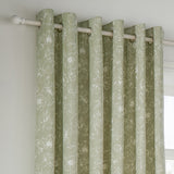 Bella Cotton Fully Lined Eyelet Curtains in Sage, showing eyelet header rings on a pole with white outline floral print on a soft sage cotton ground, hung by a bright window.