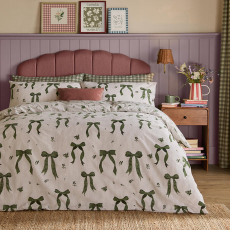 Belle Stripe Reversible Bows Duvet Cover Set in Evergreen, cream pinstripe fabric with green ribbon bow print, styled on a bed with matching pillowcases in a bedroom setting.