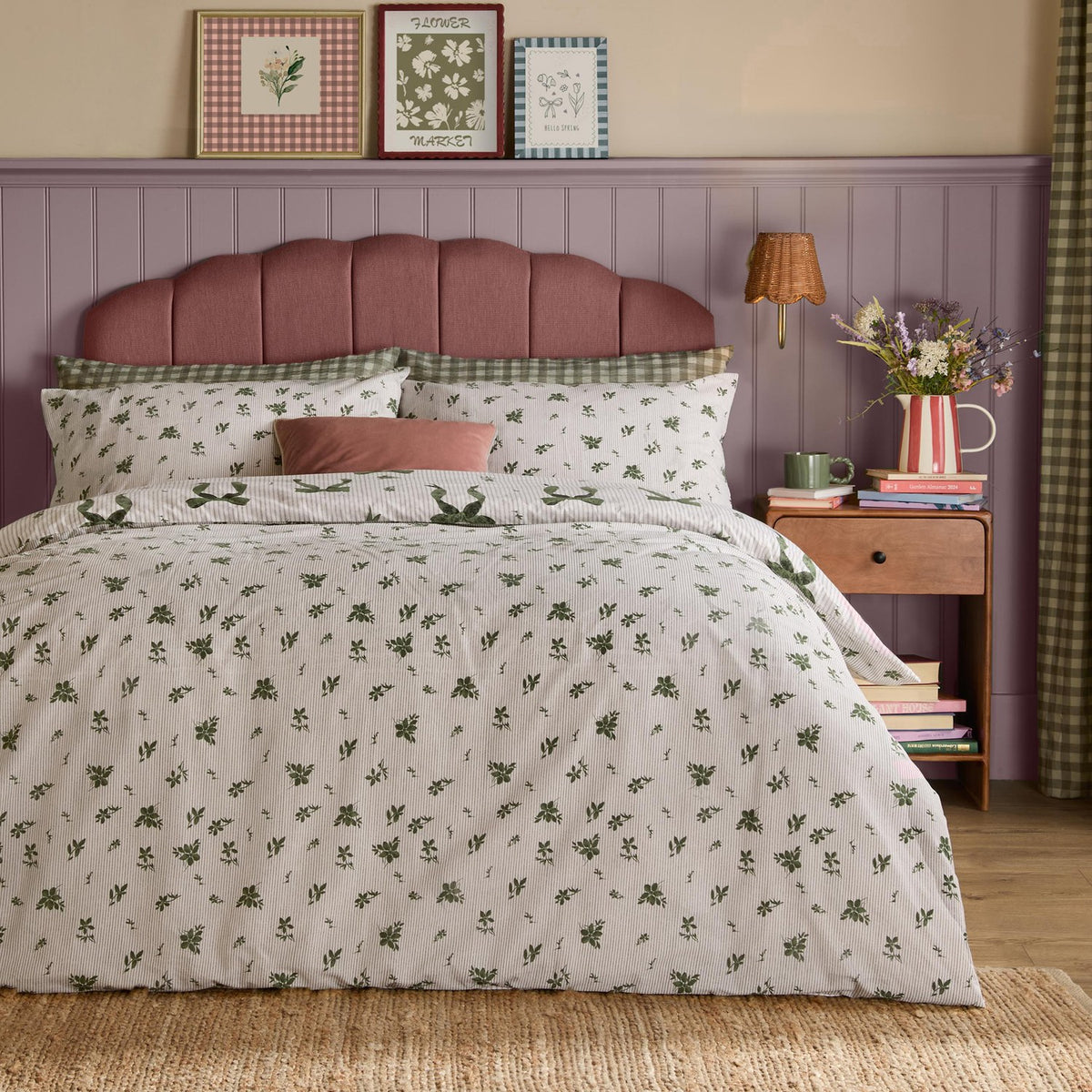 Evergreen Belle Stripe reversible bows duvet cover set with green floral pillowcases and leaf print, styled on a bed with pink headboard in a room with mauve panelling.