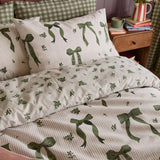 Belle Stripe Reversible Bows Duvet Cover Set in Evergreen on a bed, showing cream pinstripe fabric with green bow print, paired with matching pillowcases in a bedroom setting.