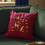 Berry Woods Plain Velvet Cushion in burgundy with embroidered woodland animals, shown on a green sofa in a living room setting.