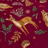 Berry Woods velvet cushion in burgundy, close-up of embroidered fawn, fox, hedgehog and owl among leaves and stars on the matt pile fabric.