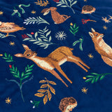 Berry Woods velvet cushion in navy, close-up of embroidered leaping deer, fox, hedgehog and foliage motifs in amber and green thread on the plush fabric.