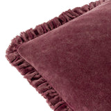 Close-up of the Bertie Velvet Cotton Cushion in plum/burgundy, showing the frayed ruffled edge trim and soft heathered velvet pile against a white background.
