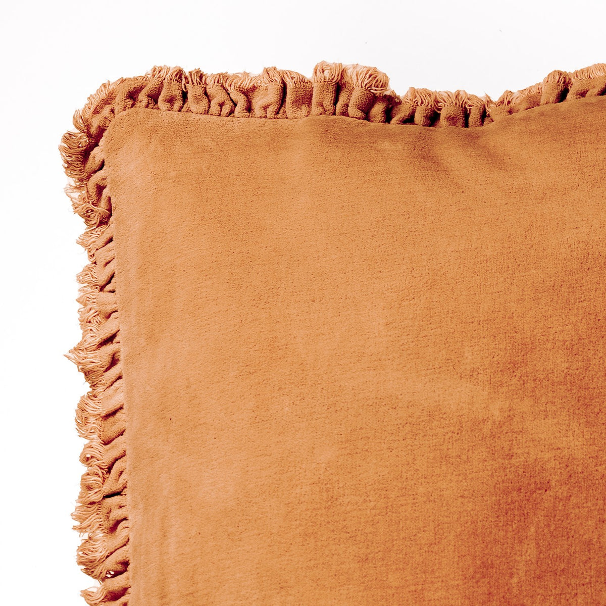 Close-up of the Bertie Velvet Cotton Cushion in rust, showing the fringed edge trim and soft washed velvet fabric against a plain white background.
