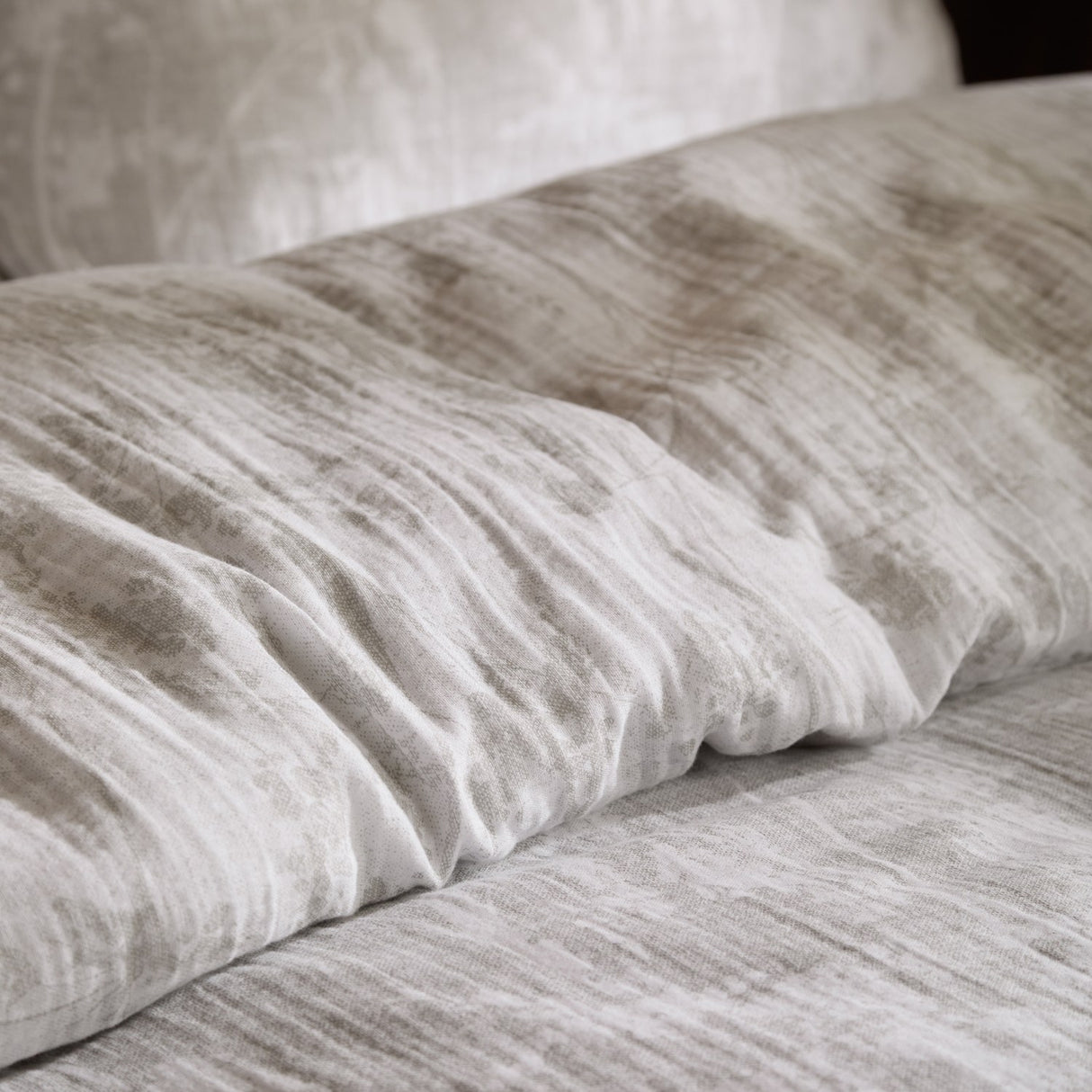 Close-up of the Braeflower Cotton Duvet Cover Set in natural, showing crinkled cotton muslin with a soft floral toile print on pillow and bedding.