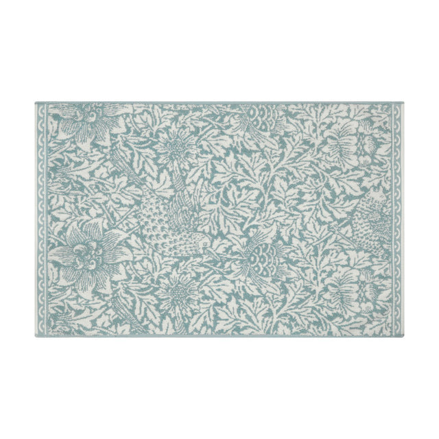 Rectangular Bird and Anemone cotton bath mat in slate blue floral print on cream, with a narrow scalloped border, shown on a plain white background.