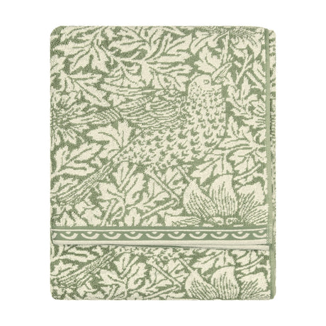 Folded Bird & Anemone jacquard cotton towel in sage green, showing a leafy foliage and bird pattern with a scalloped border, on a plain white background.