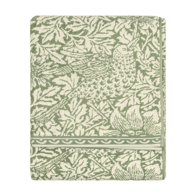 Folded Bird & Anemone jacquard cotton towel in sage green, showing a leafy foliage and bird pattern with a scalloped border, on a plain white background.
