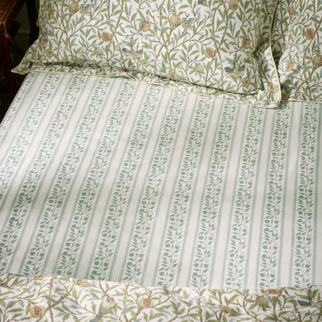 Bird & Pomegranate percale cotton fitted sheet in sage, striped leaf pattern on a bed with matching floral pillowcases in green and cream tones.