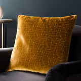 Bloomsbury Abstract Velvet Cushion in mustard, square 50x50cm with raised geometric cut-velvet pattern, styled on a dark grey armchair.