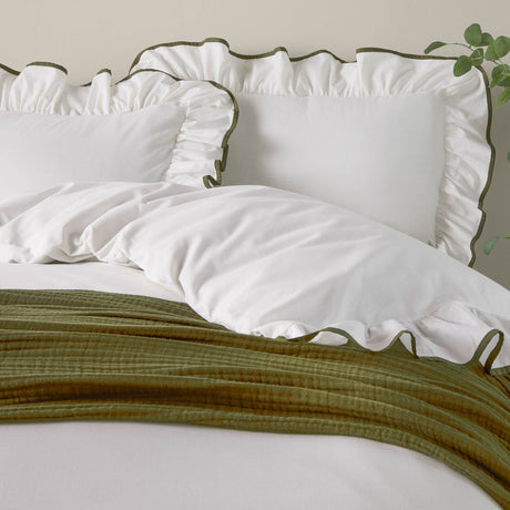 Blousey Cotton Plain Duvet Cover Set in Olive, showing white cotton bedding with ruffled edges and olive piped trim, styled with an olive throw on a bed.