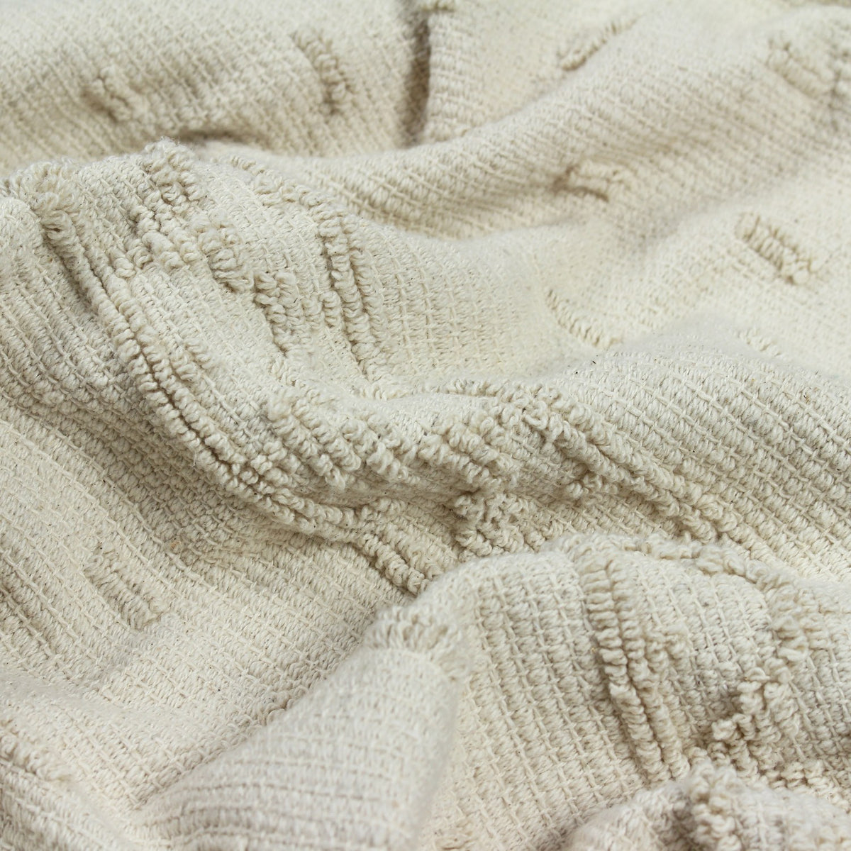 Close-up of the Boho Geometric Cotton Throw in cream, showing raised tufted geometric blocks creating a low-relief textured pattern on soft cotton fabric.