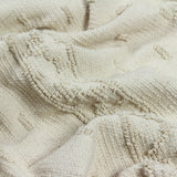 Close-up of the Boho Geometric Cotton Throw in cream, showing raised tufted geometric blocks creating a low-relief textured pattern on soft cotton fabric.