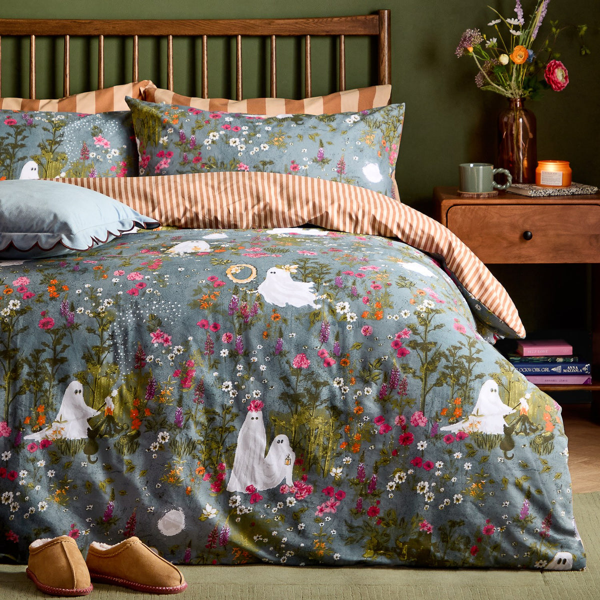 Grey-blue Bootanical Forest Duvet Cover Set on a wooden bed frame, printed with wildflowers, foxgloves and ghost figures, rust-and-cream striped reverse, matching pillowcases, green-walled bedroom.