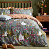 Grey-blue Bootanical Forest Duvet Cover Set on a wooden bed frame, printed with wildflowers, foxgloves and ghost figures, rust-and-cream striped reverse, matching pillowcases, green-walled bedroom.