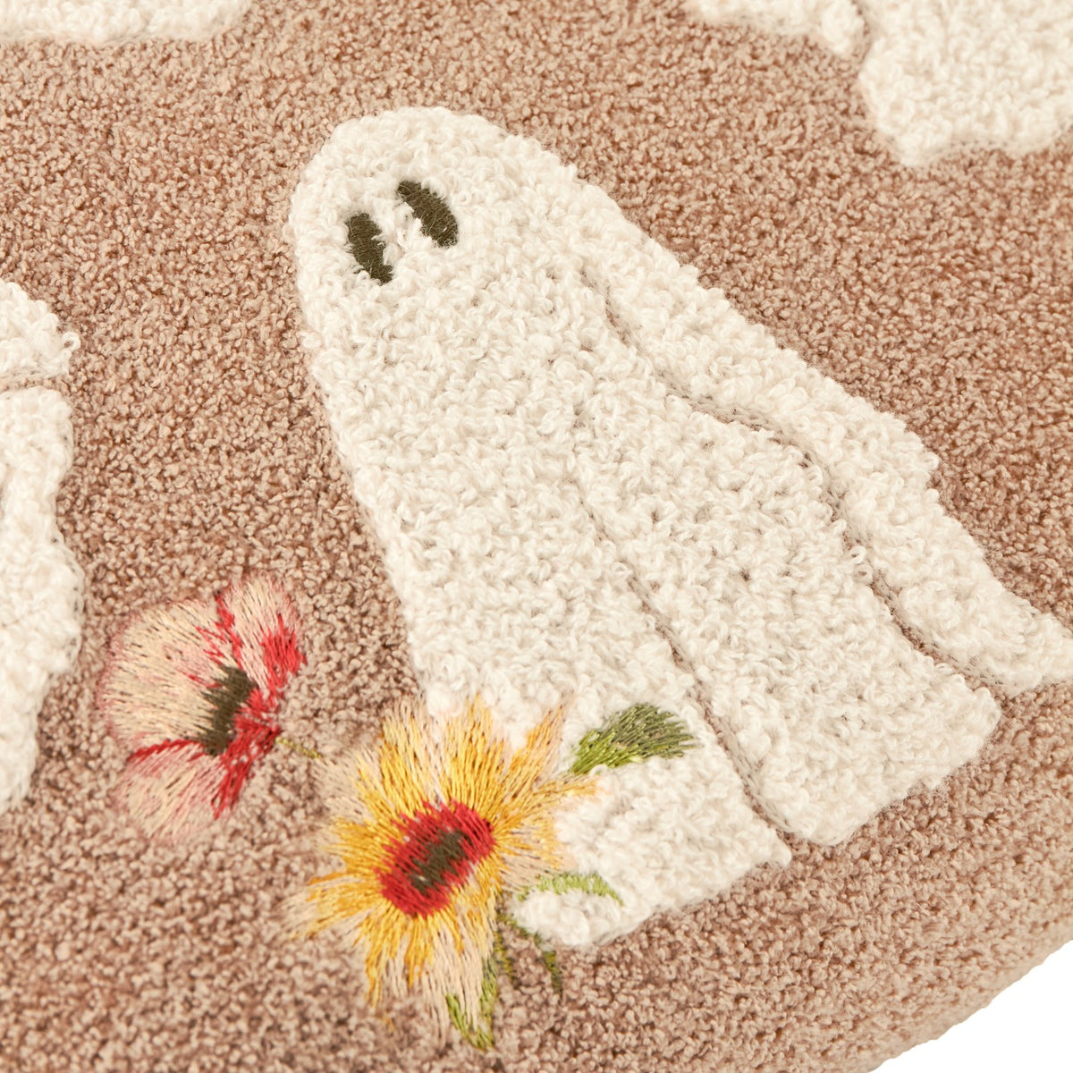 Close-up of the Bootanical Floral Velvet Cushion in natural beige, showing a tufted white ghost with embroidered face and red, yellow and pink floral embroidery in raised boucle texture.