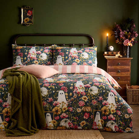 Bootanical Reversible Floral Duvet Cover Set in multi, shown on a bed with ghost and pumpkin print on teal-green ground, styled with pink cushions and reverse pink stripe, in a green bedroom setting.