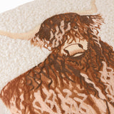 Close-up of the Boucle Highland Cow cushion showing embroidered brown and tan fringe detail with pale horns on a cream textured boucle base.