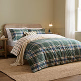 Braemar Check Cotton Reversible Duvet Cover Set in Forest/Navy tartan-style plaid, styled on a bed with matching pillowcases in a bedroom setting with rattan headboard and cream throw.