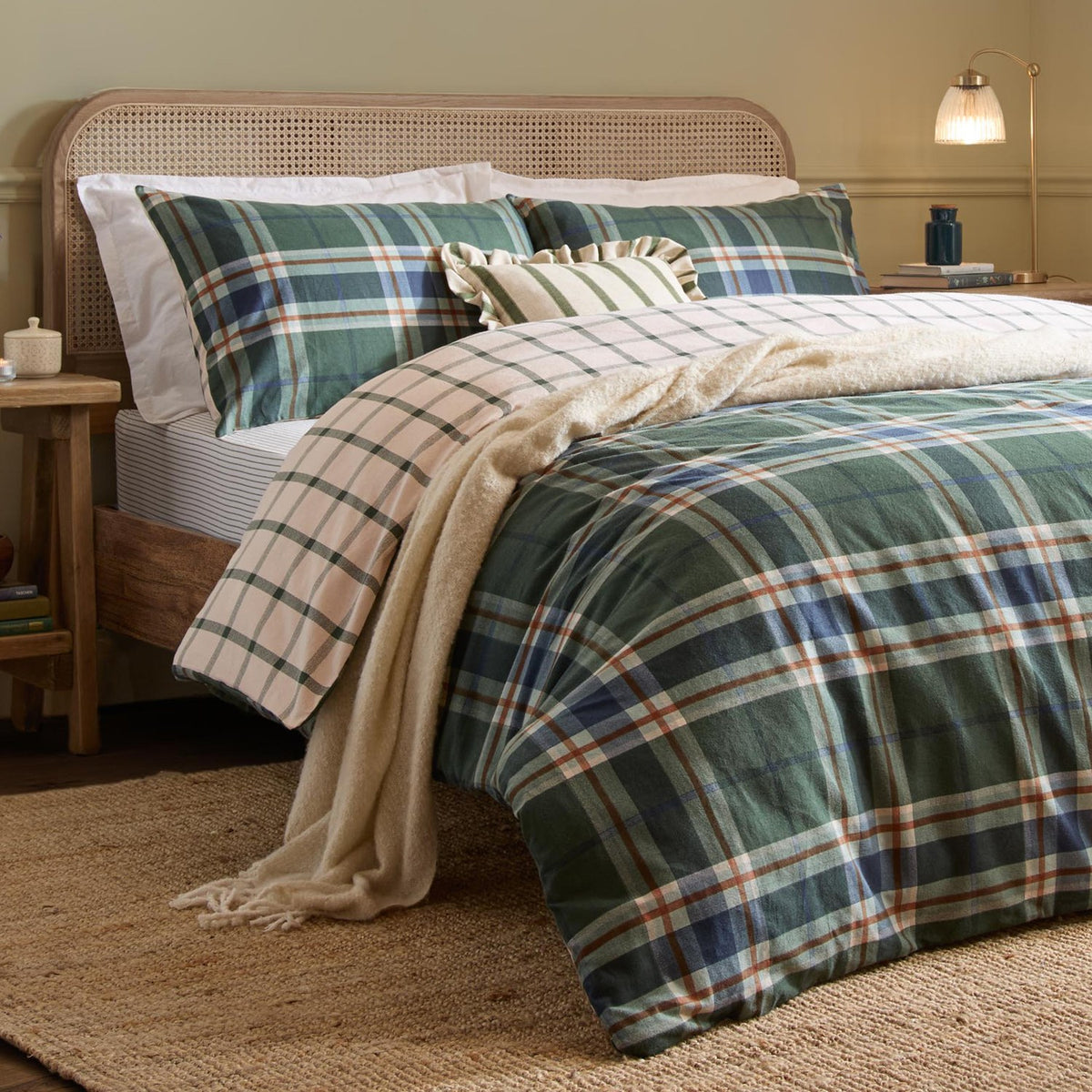 Braemar Check Cotton Reversible Duvet Cover Set in Forest/Navy tartan-style plaid, shown on a bed with matching pillowcases, cream ruffled cushion, and beige throw in a bedroom setting.