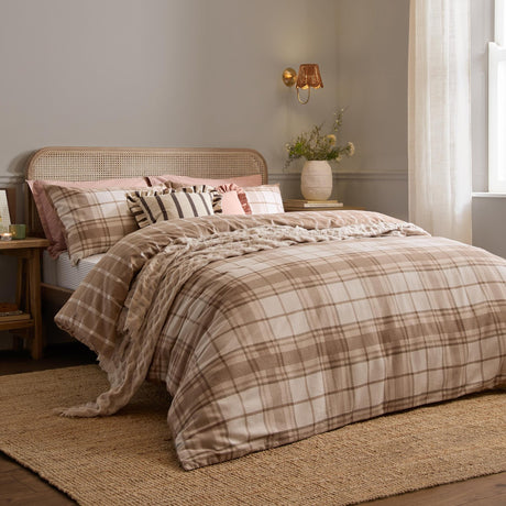 Braemar Check Cotton Reversible Duvet Cover Set in natural beige and cream tartan-inspired check, styled on a bed with matching pillowcases in a bedroom with rattan headboard.
